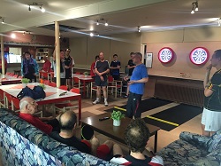 Manfred richt zich tot de aanwezige leden voor de officiële opening van de dartbanen
